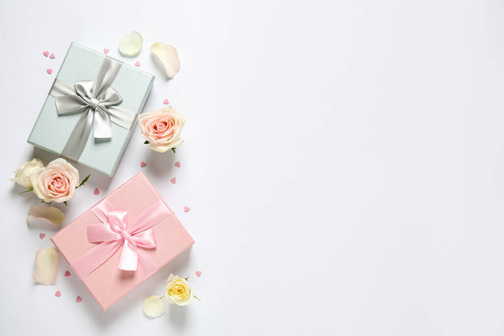 Elegant gift boxes and beautiful flowers on white background, flat lay. Space for text - Photo, Image