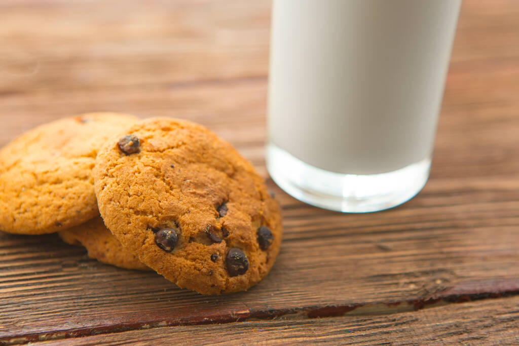 Biscotti al cioccolato e un bicchiere di latte sul tavolo di legno - Foto, immagini