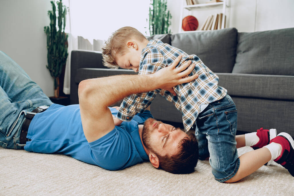 Père et fils jouent ensemble sur le tapis à la maison - Photo, image