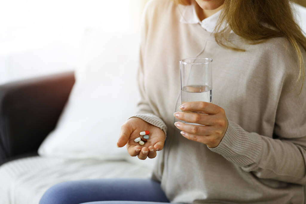 Detailní záběr žena drží pilulky čas brát léky, lék na bolest hlavy. Koncepce medicíny během sebeizolace a pandemie koronaviru - Fotografie, Obrázek