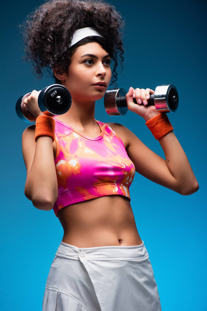 göndör fiatal nő gyakorló súlyzók kék - Fotó, kép