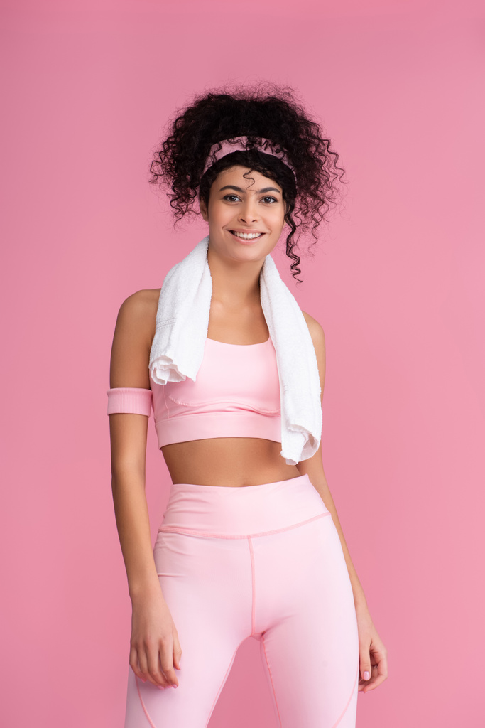 happy young sportswoman with towel on shoulders standing isolated on pink  - Photo, Image