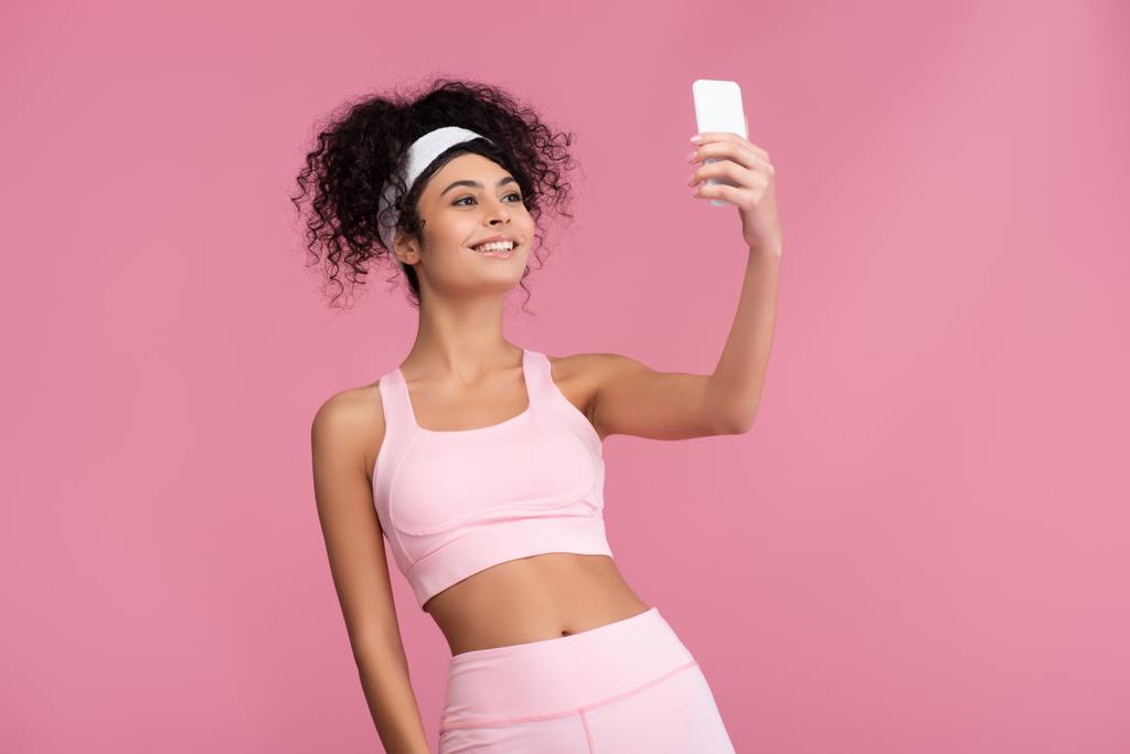 Ευτυχισμένη νεαρή αθλήτρια που παίρνει selfie σε smartphone απομονωμένο σε ροζ  - Φωτογραφία, εικόνα