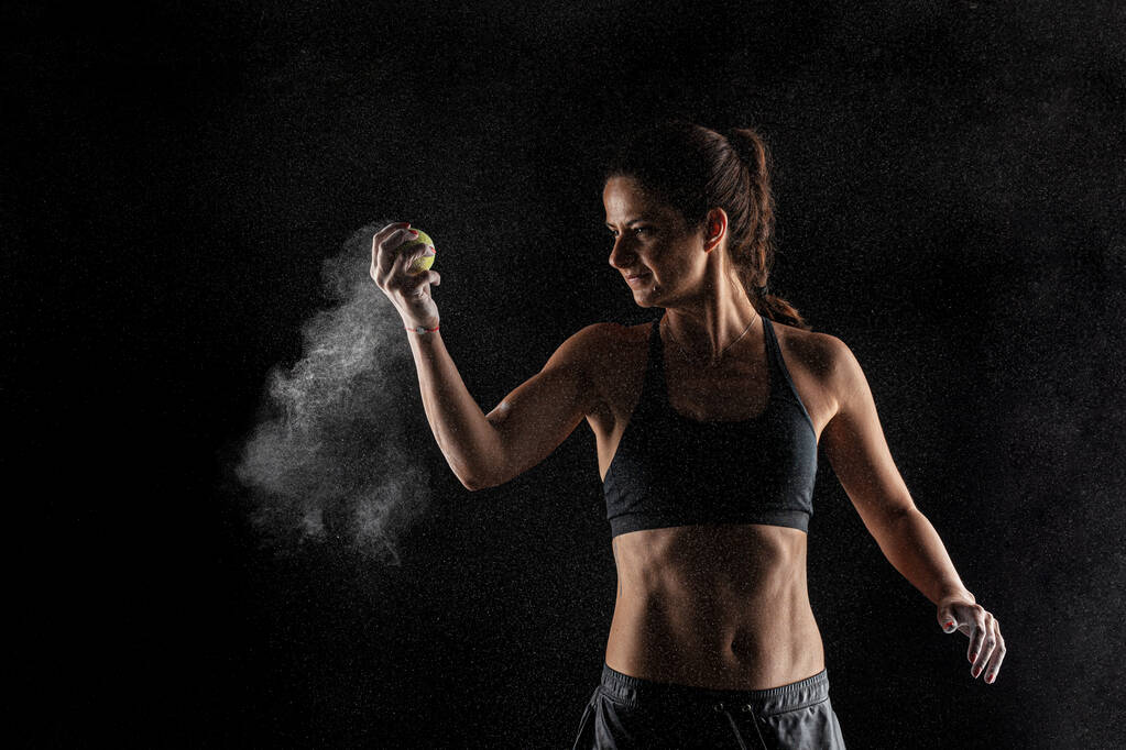 Tennisser kirl met magnesiumpoeder op haar handen, grijpen een bal met stof zichtbaar. - Foto, afbeelding