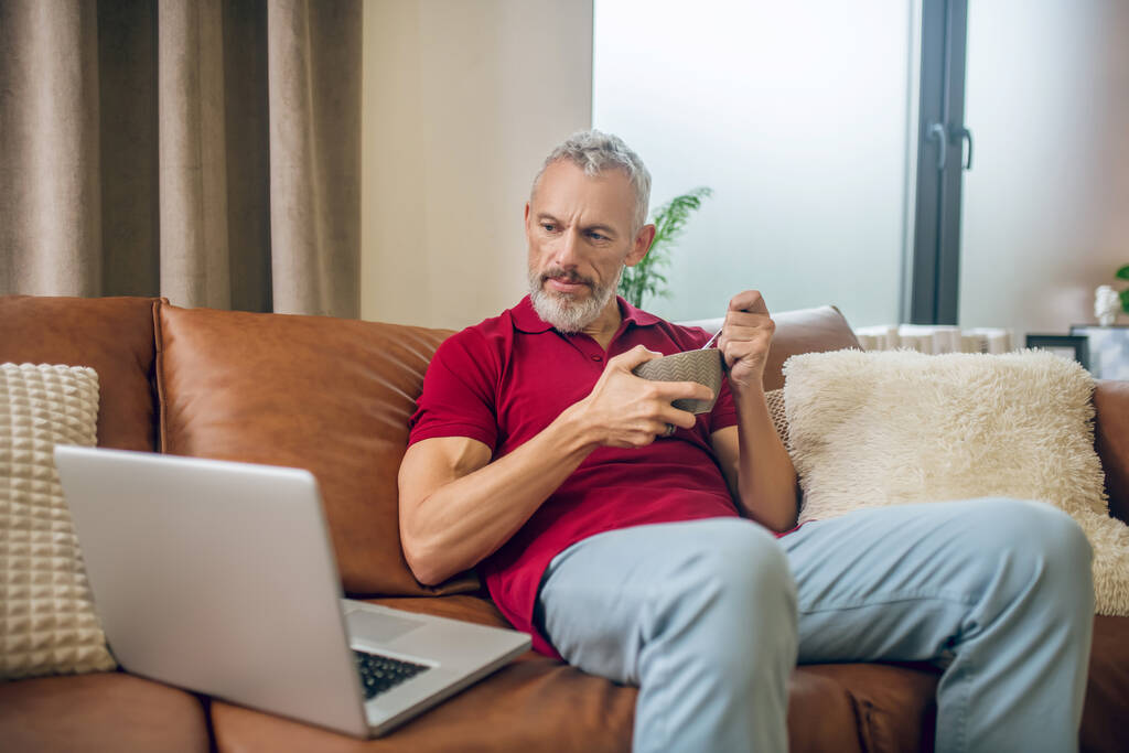 Homem de cabelos grisalhos almoçando e assistindo a um vídeo - Foto, Imagem