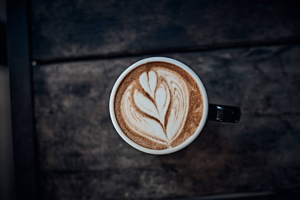 Tasse heißen Latte-Art-Kaffee auf Holztisch, Fokus auf weißen foa - Foto, Bild
