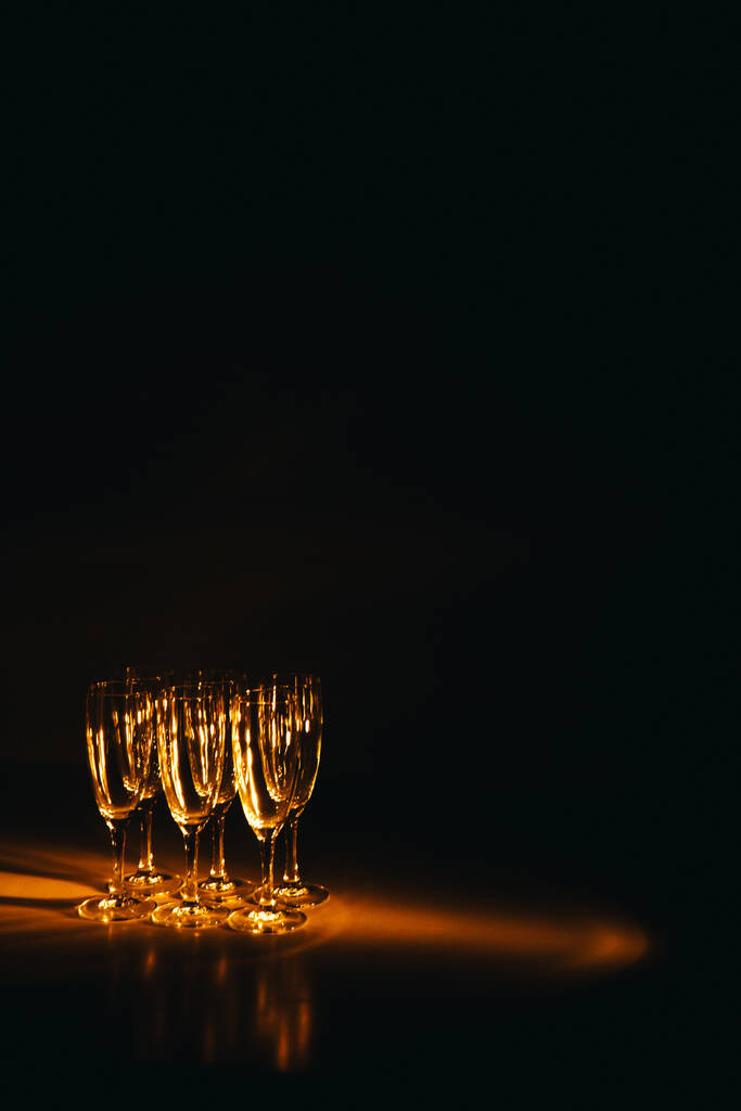 Un grupo de varias copas de champán está bellamente iluminado sobre un fondo oscuro. Una composición festiva. Espacio para texto - Foto, imagen