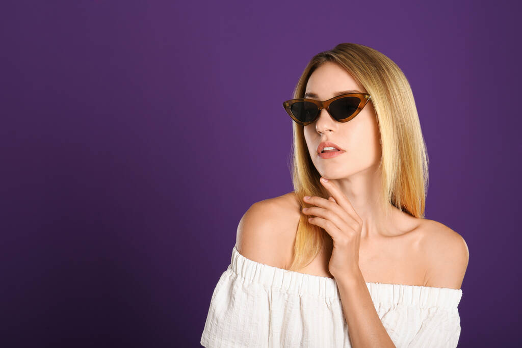 Bella donna in eleganti occhiali da sole su sfondo viola. Spazio per testo - Foto, immagini
