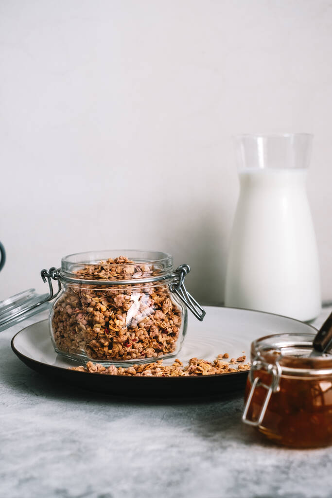 Granola in glass jar and carafe of milk on a table. High quality photo - Photo, Image