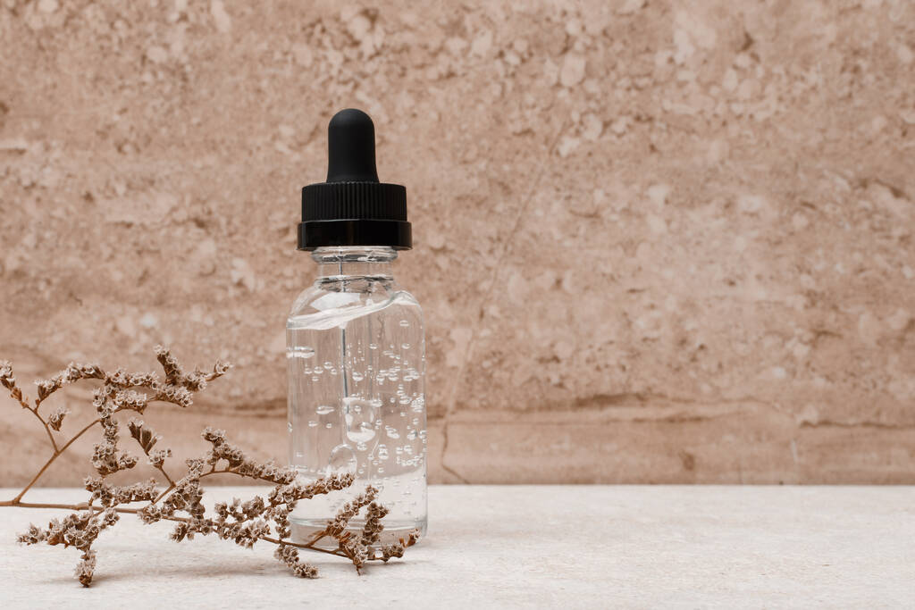 Skin serum in transparent bottle with black cap against marble background with space for text - Photo, Image