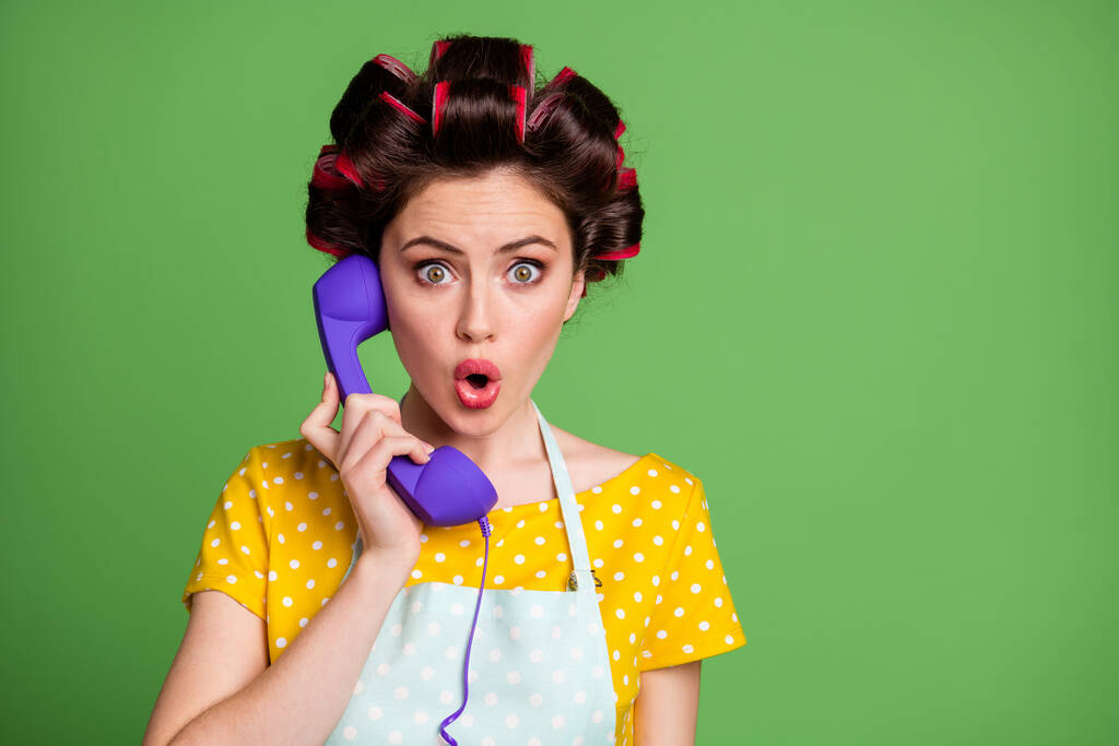 Foto erstaunt Retro-Vintage-Mädchen klingeln Telefonkabel hören Betrüger sagen sprechen sprechen unglaubliche Informationen tragen gelb gepunktetes T-Shirt Kleid Haarrollen isoliert grüne Farbe Hintergrund - Foto, Bild