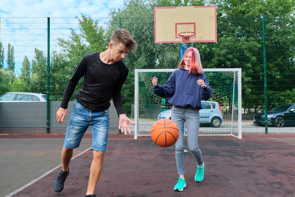 Підлітки хлопець і дівчина на відкритому баскетбольному майданчику грають на вуличному баскетболі
 - Фото, зображення