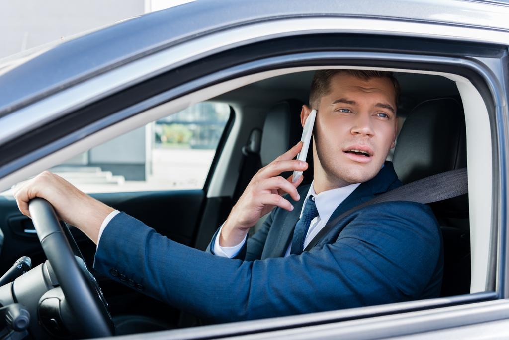 車を運転しながら窓を見ているビジネスマンやスマートフォンで話しているビジネスマン - 写真・画像