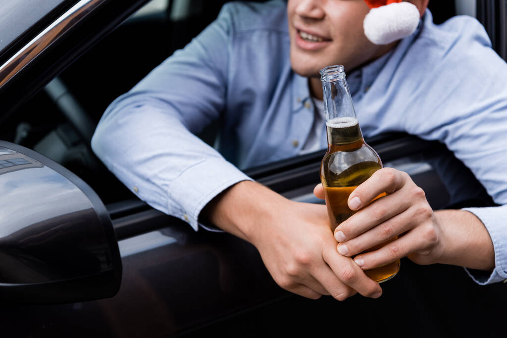 partial view of man looking out car window while holding whiskey, blurred background - Photo, Image