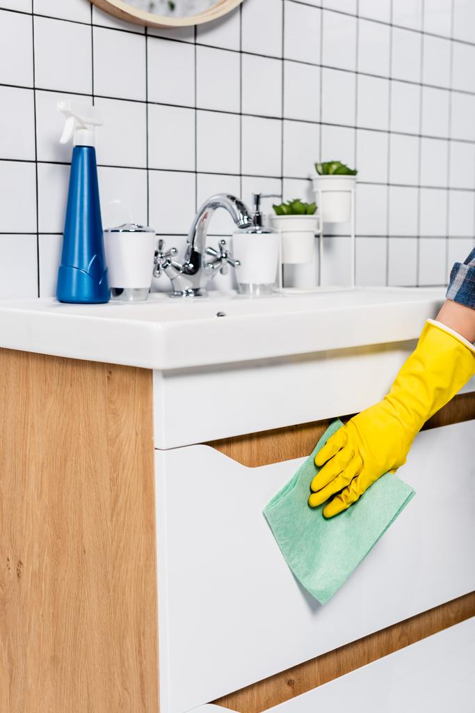 Обрезанный вид женщины уборки стороне раковины с тряпкой возле моющего средства в ванной комнате  - Фото, изображение