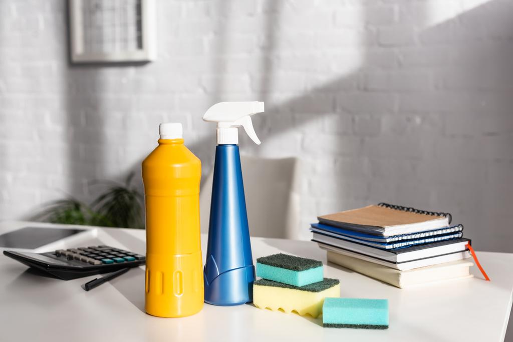 Botellas de detergentes y esponjas cerca de cuadernos y calculadora en la mesa  - Foto, Imagen