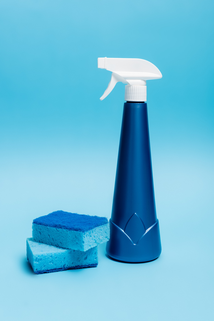 Frasco azul de detergente y esponjas sobre fondo azul - Foto, imagen