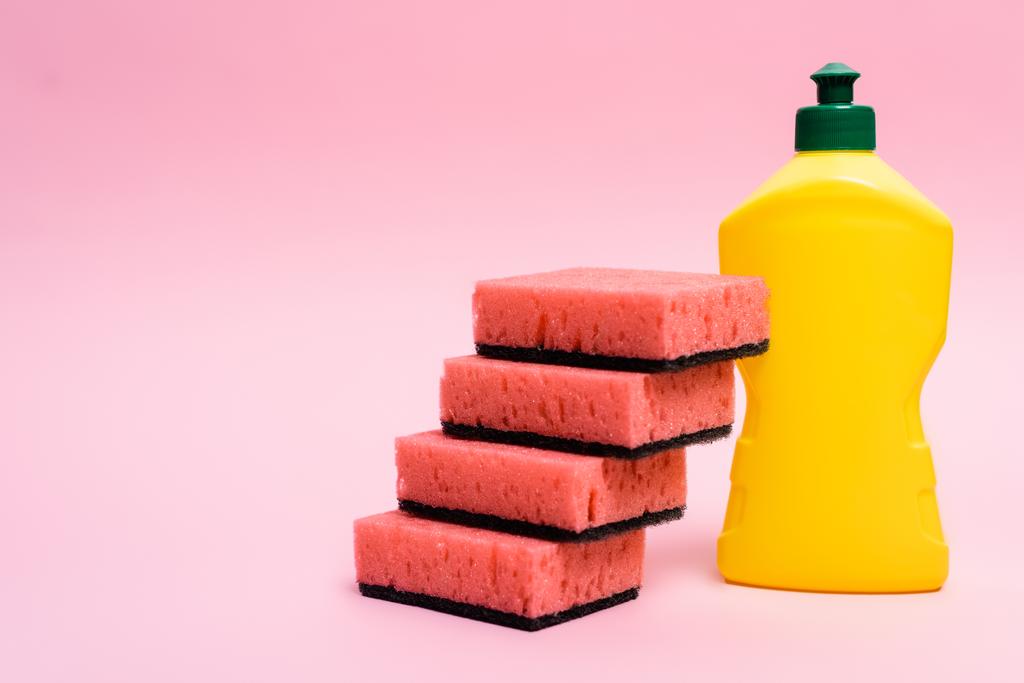 Esponjas cor-de-rosa e garrafa de líquido de lavar louça sobre fundo rosa - Foto, Imagem