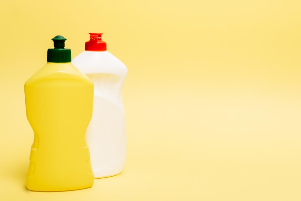 Botellas de líquido lavavajillas sobre fondo amarillo con espacio para copiar - Foto, Imagen
