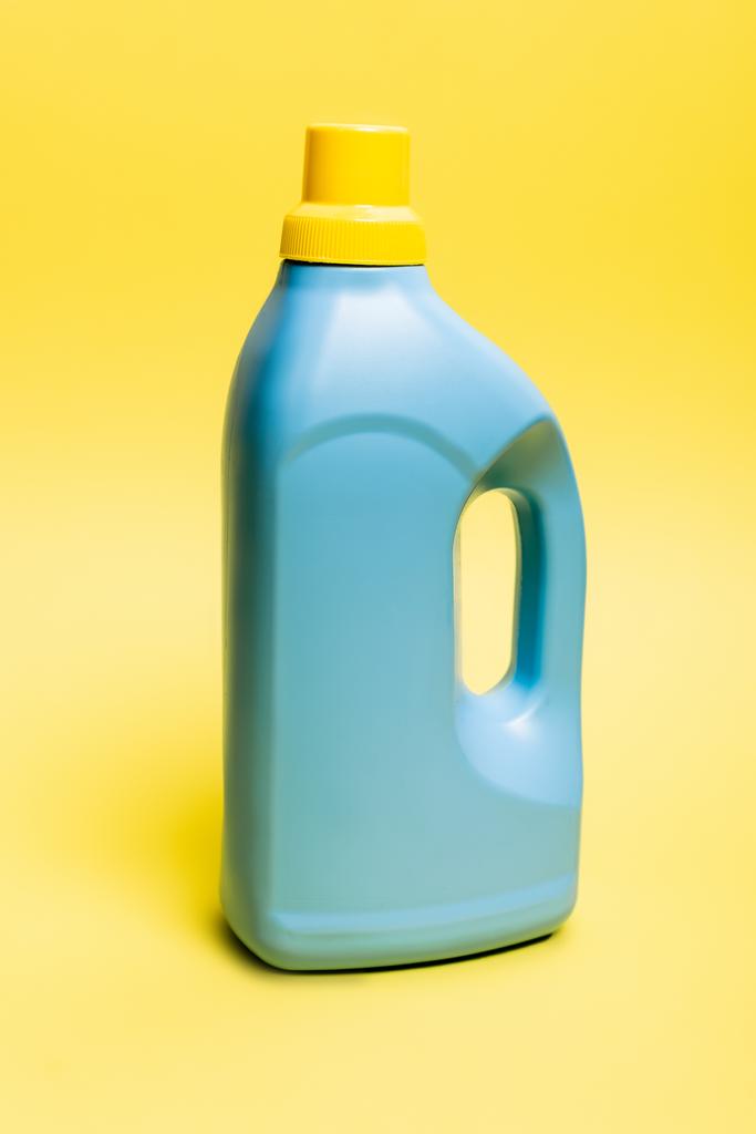 黄色の背景に洗剤の青いボトル - 写真・画像