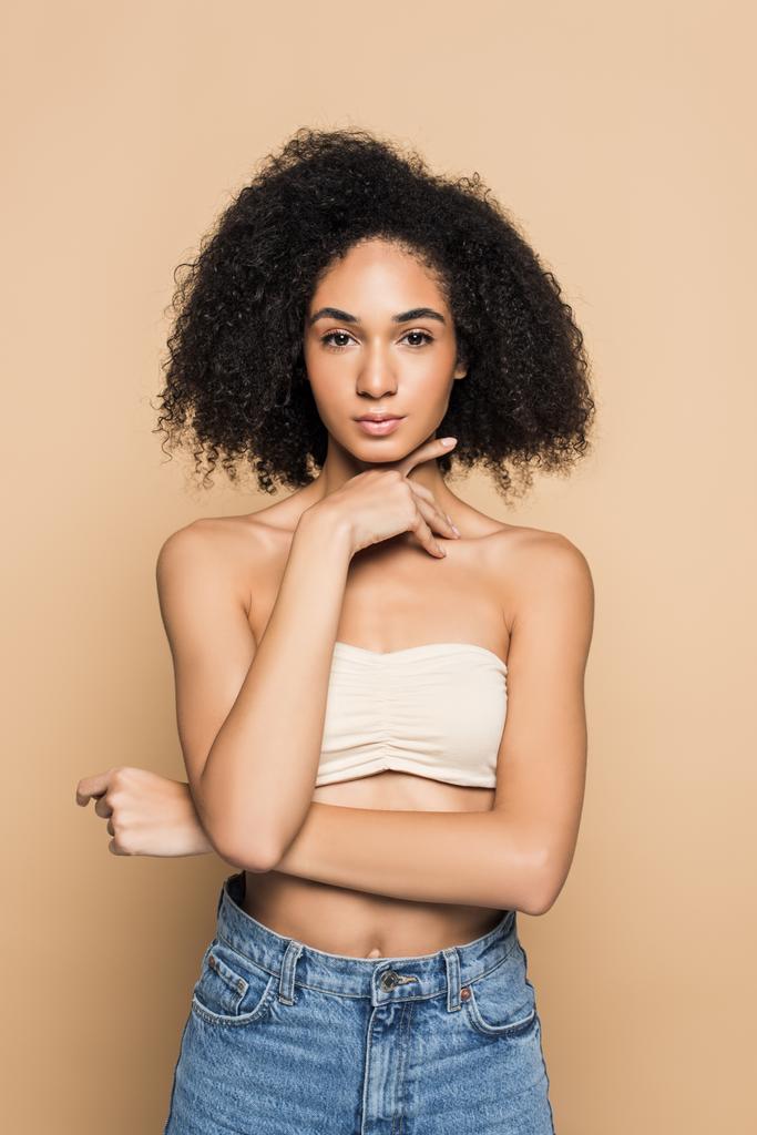curly african american woman with bare shoulders looking at camera isolated on beige  - Photo, Image