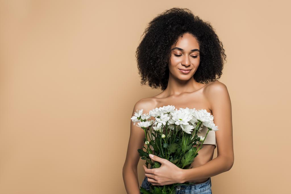 ベージュで孤立した花を持つ幸せなアフリカ系アメリカ人女性 - 写真・画像