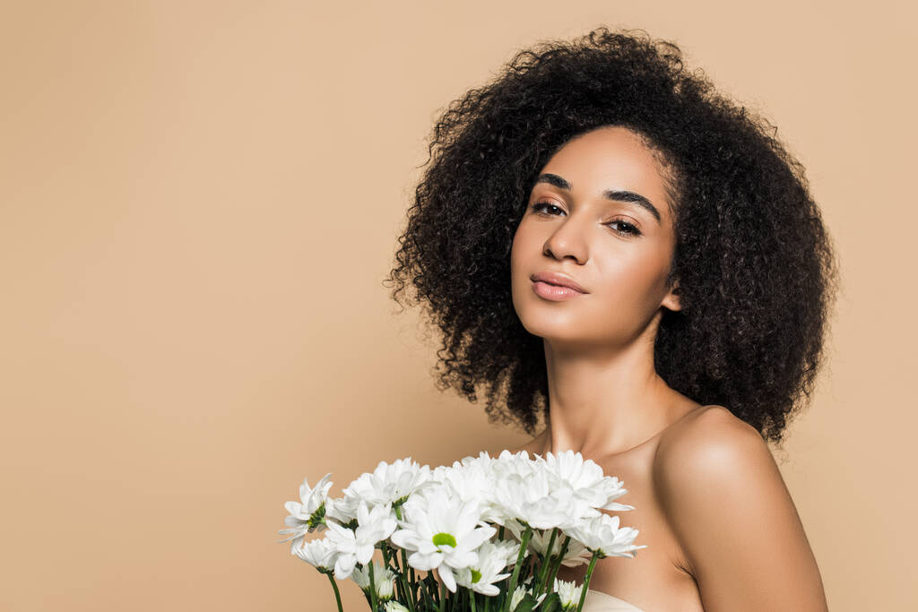 ricci donna africana americana con spalle nude vicino a fiori isolati su beige - Foto, immagini