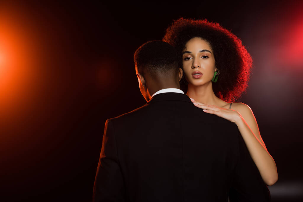 élégante femme afro-américaine embrassant l'homme en costume sur noir - Photo, image