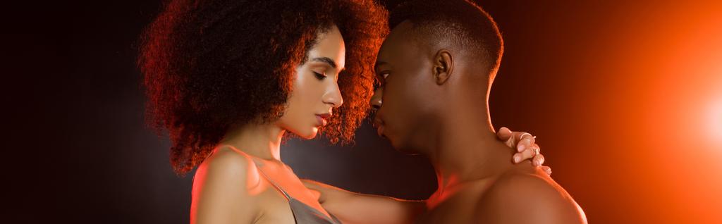 黒のバナーで巻き毛の女性を誘惑する恥知らずのアフリカ系アメリカ人男性の側面図 - 写真・画像