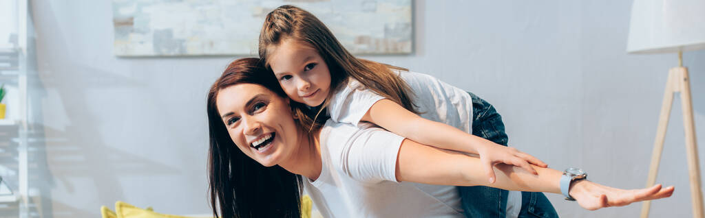 幸せな母親と娘と手を伸ばしてカメラを見ている間にピギーバックと一緒に背景にぼやけた画像,バナー - 写真・画像