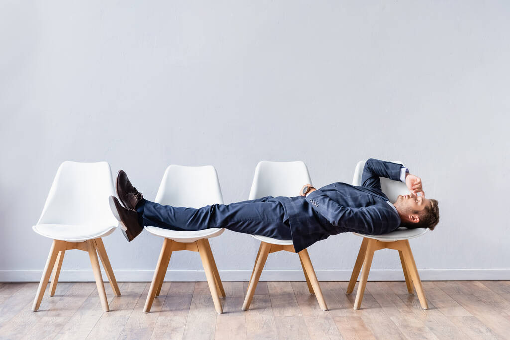 Бізнесмен у костюмі лежить на стільцях під час очікування співбесіди
  - Фото, зображення