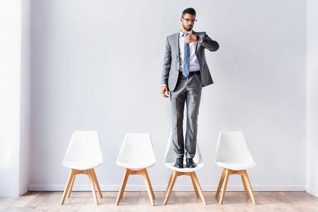 Επιχειρηματίας με κοστούμι κοιτάζοντας ρολόι χειρός, ενώ περιμένει στην αίθουσα  - Φωτογραφία, εικόνα