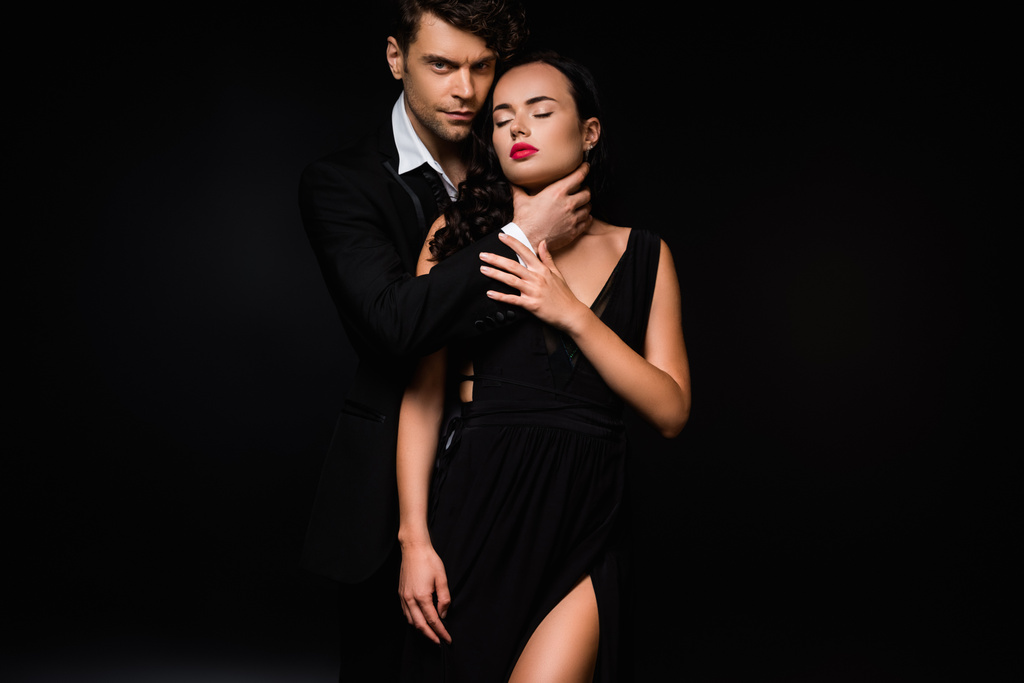 apaixonado homem asfixia sexy e submisso mulher no vestido isolado no preto  - Foto, Imagem