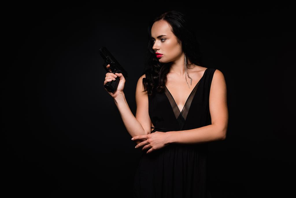 Siyah giysili esmer kadın, siyah üzerine izole edilmiş silah taşıyor.  - Fotoğraf, Görsel