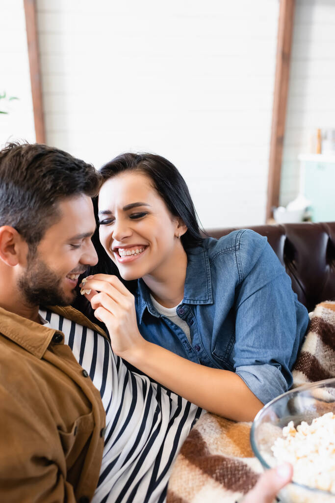 excitada mulher com olhos fechados alimentando namorado com pipoca, foreground borrado - Foto, Imagem