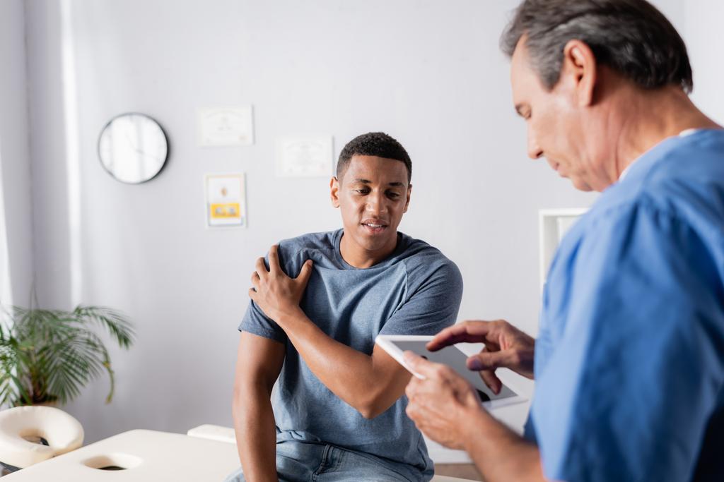 afro-amerikai beteg szenved fájdalom közelében orvos segítségével digitális tabletta  - Fotó, kép