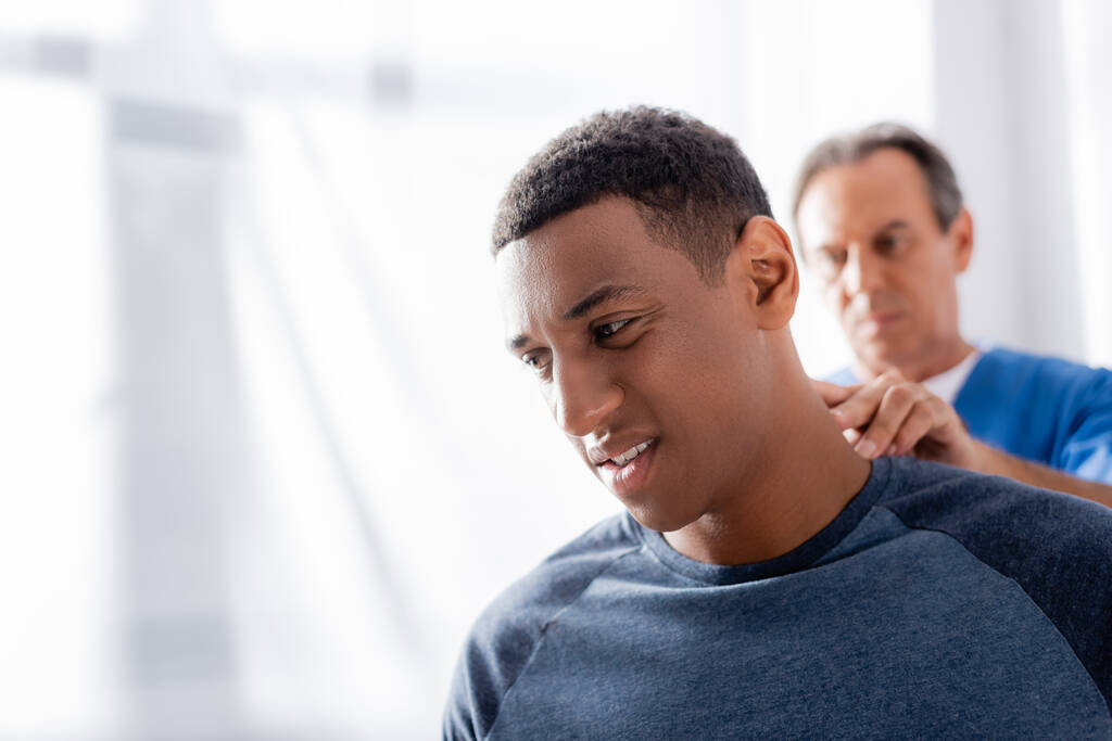 hämärtynyt terapeutti hierova afrikkalainen amerikkalainen potilas klinikalla - Valokuva, kuva