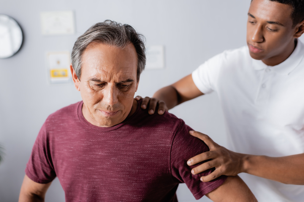hämärtynyt afrikkalainen amerikkalainen fysioterapeutti työskentelee kypsän miehen kanssa klinikalla - Valokuva, kuva