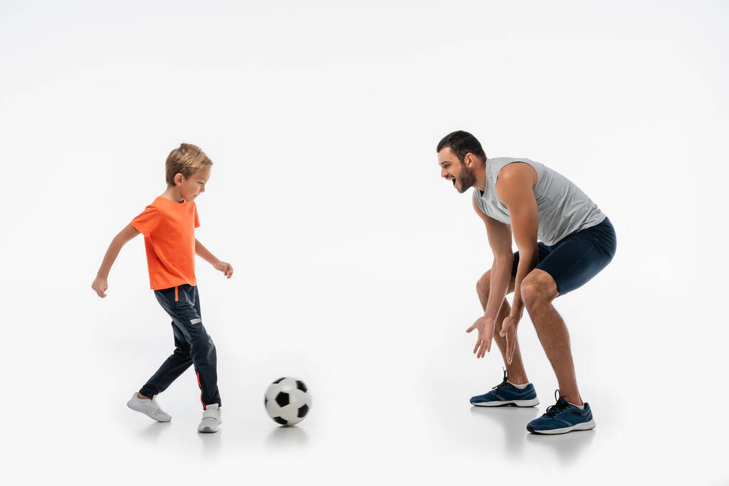 excited father and son in sportswear playing football on white - Photo, Image