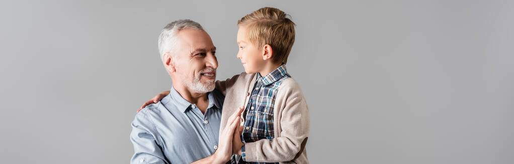 onnellinen mies antaa yläfemma pojanpoika pitäen häntä eristetty harmaa, banneri - Valokuva, kuva