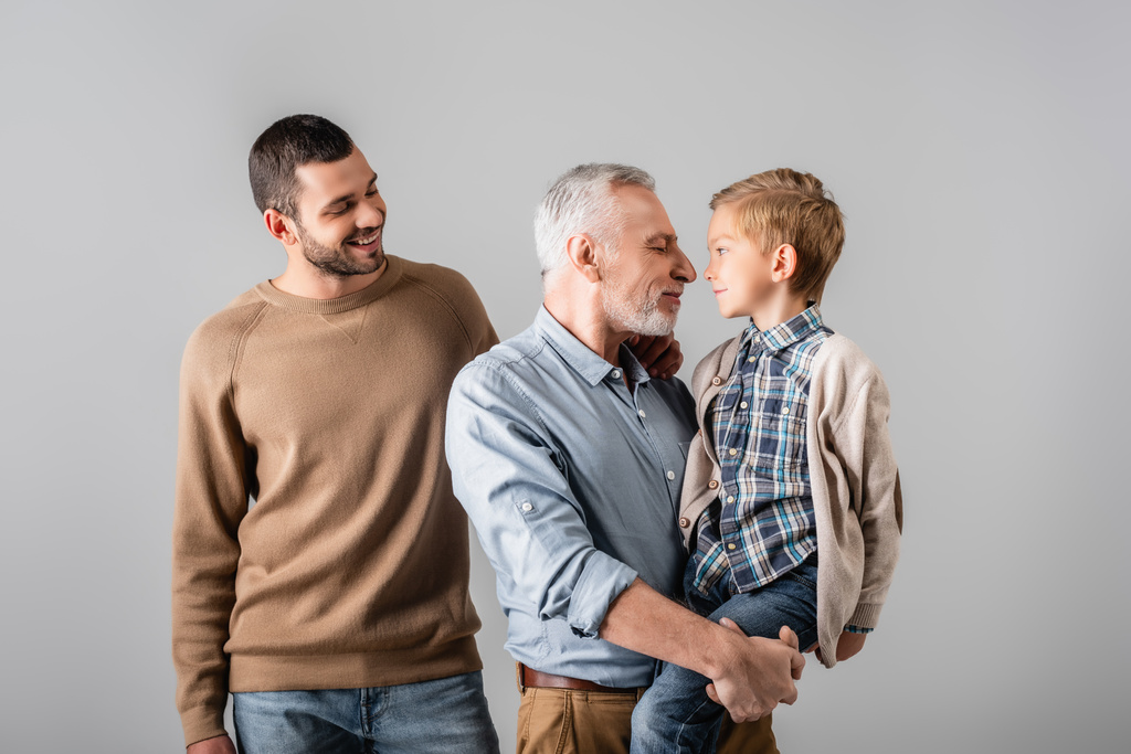 happy mature man holding grandson near smiling son isolated on grey - Photo, Image