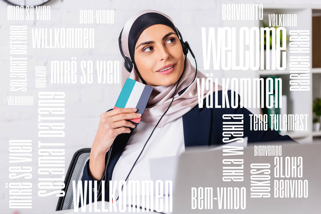 glimlachende Arabische tolk in koptelefoon met digitale vertaler op wazige voorgrond, welkom woord in verschillende talen illustratie - Foto, afbeelding