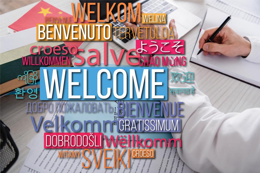 Dizüstü bilgisayarın ve sözlüklerin yakınındaki çevirmen yazısının kısmi görünümü, farklı dillerde yazılmış kelimeler. Çevirisi: "Hoş geldiniz" - Fotoğraf, Görsel