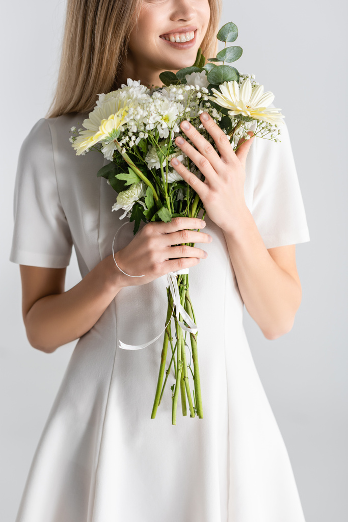 vista ritagliata di giovane donna sorridente mentre tiene i fiori isolati sul grigio - Foto, immagini