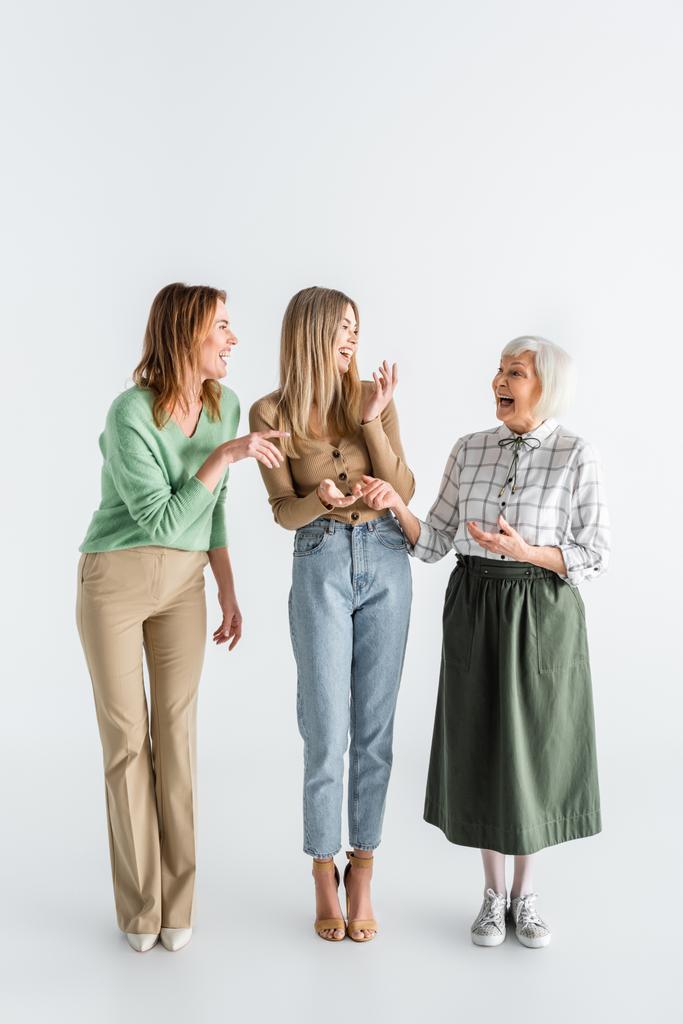повна довжина трьох поколінь щасливих жінок, що сміються, стоячи на білому
 - Фото, зображення