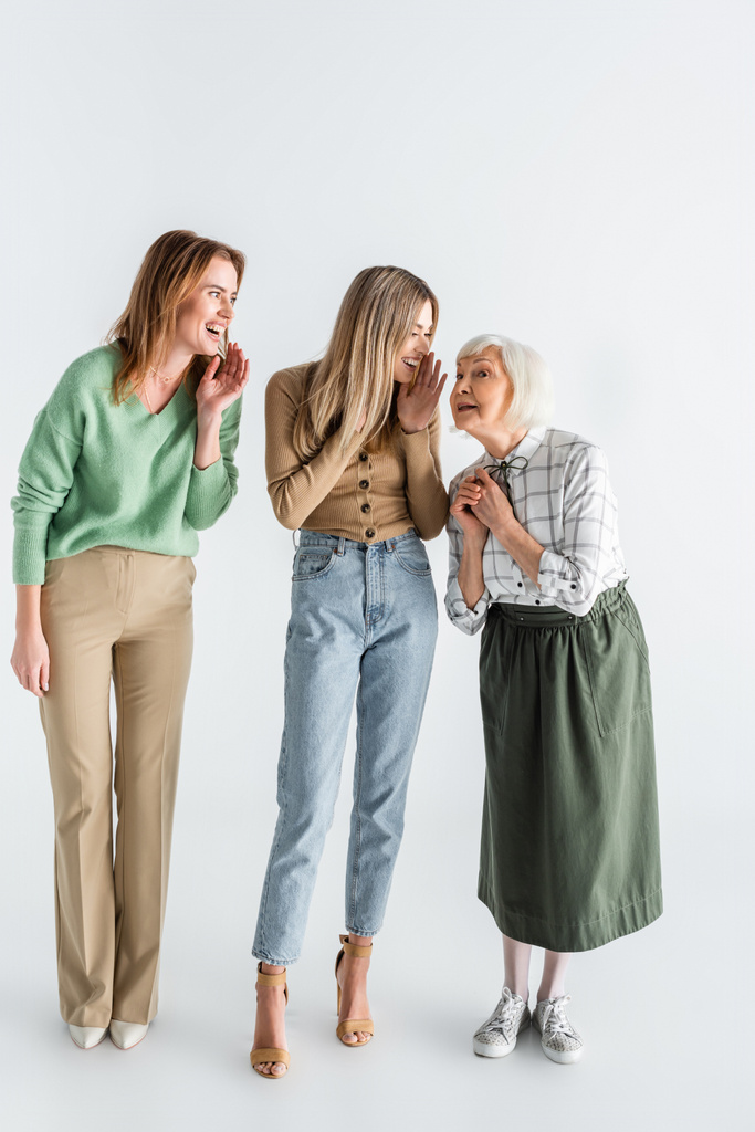piena lunghezza di tre generazioni di donne felici sorridenti mentre spettegolano sul bianco - Foto, immagini