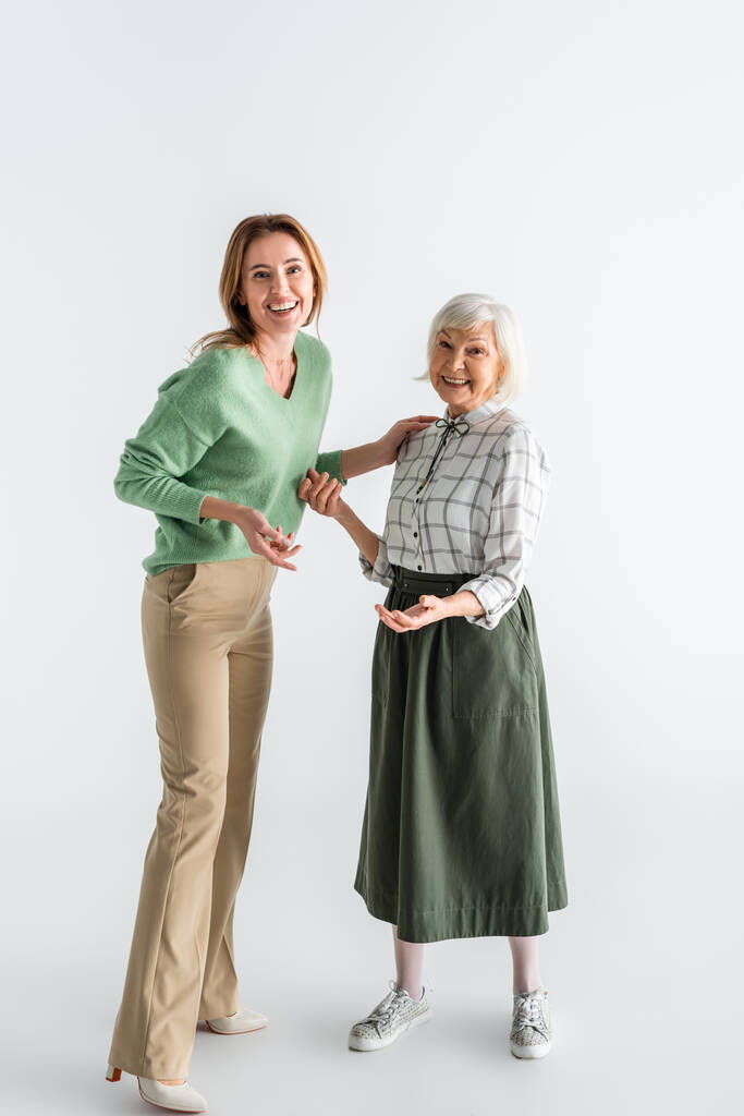 plná délka generace šťastných žen usmívajících se při stání na bílém - Fotografie, Obrázek