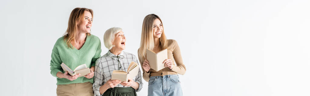 three generation of cheerful women holding books isolated on white, banner  - Photo, Image