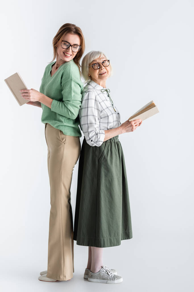 pleine longueur de la femme âgée et fille dans des lunettes tenant des livres sur blanc - Photo, image