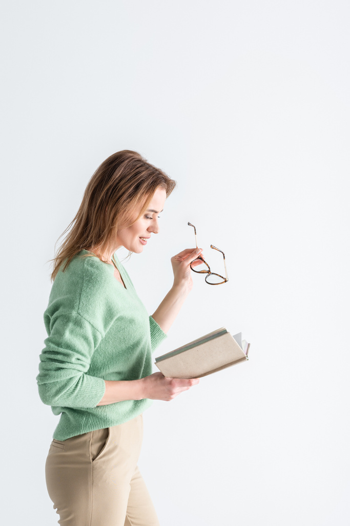 cheerful woman holding glasses and reading book isolated on white - Photo, Image